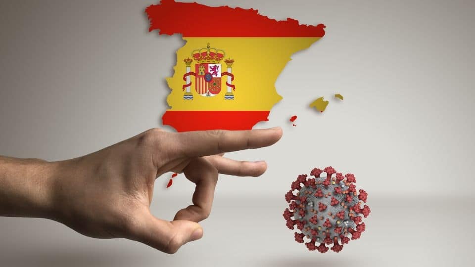 Una mano caccia via un virus con la spagna sullo sfondo
