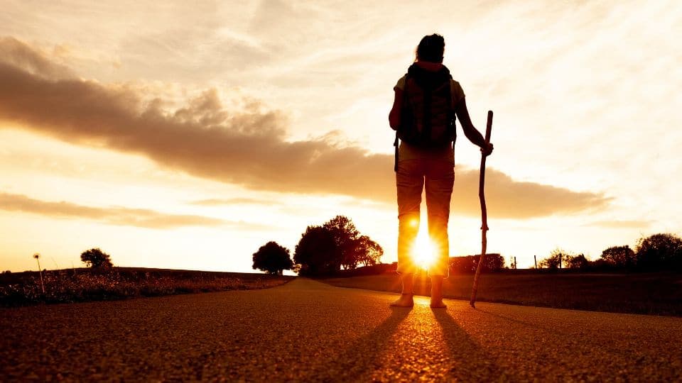 Una pellegrina cammina a piedi scalzi al tramonto