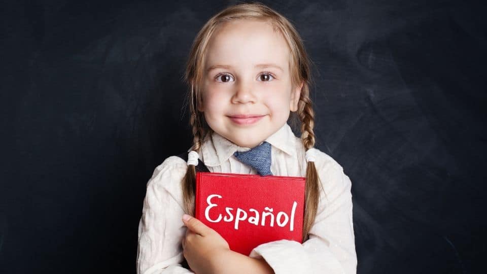 Bambina ha tra le braccia un libro di spagnolo