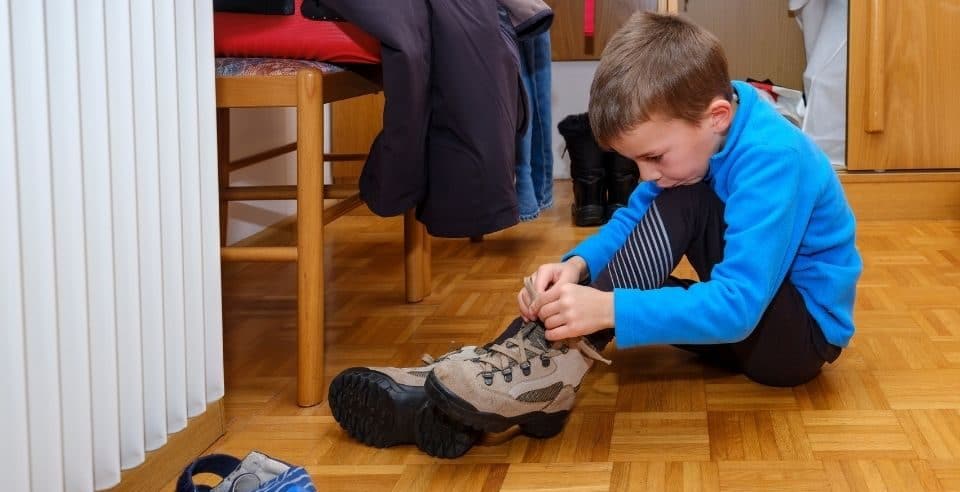Un bambino allaccia le scarpe da trekking